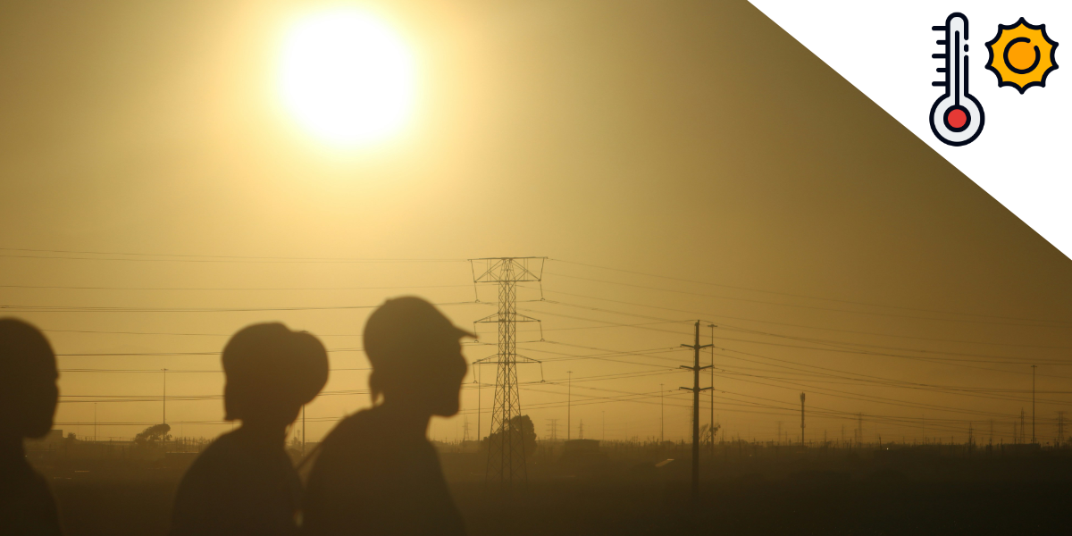 Silhouetten von Menschen vor einem dunstigen Sonnenuntergang.