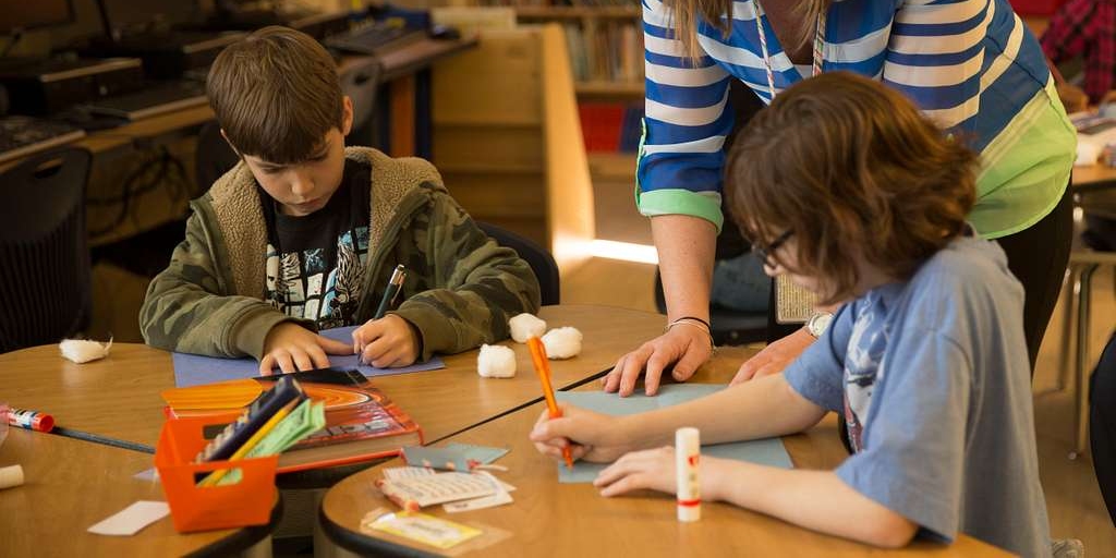 Lehrerin unterstützt ihre Schüler:innen bei Aufgaben